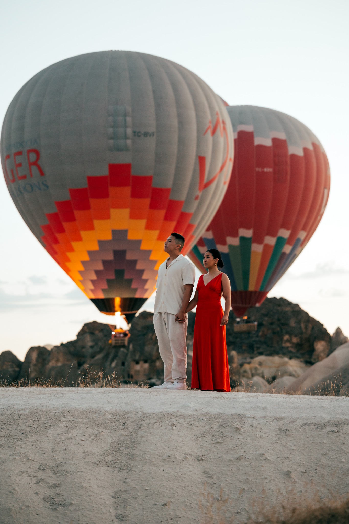 Tashna and Joshua posing in Cappadocia with hot air balloons behind them